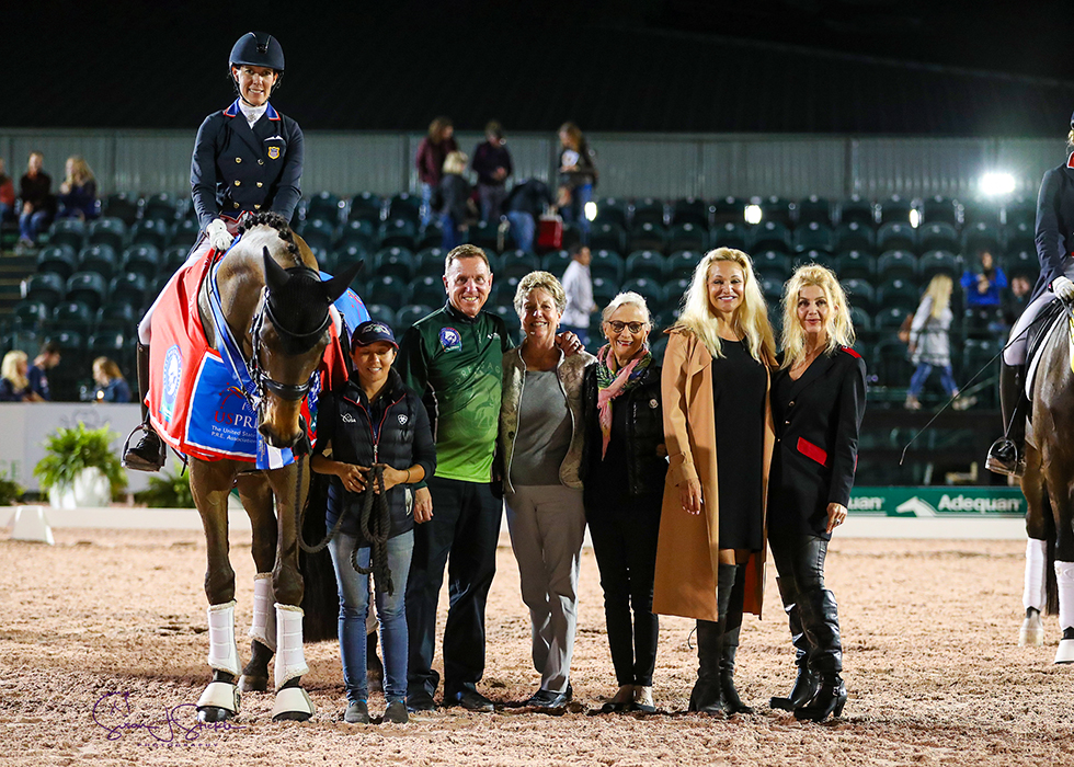 Olivia LaGoy-Weltz in the prize-giving with groom Nicole Ardito, Allyn Mann of Adequan®, judge Jane Weatherwax and Janne Rumbough, Kim Van Kampen and Jane Bistline of US P.R.E.. ©️Susan Stickle.